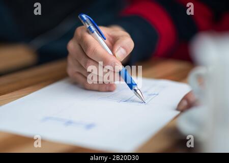 The hand of the designer with a pen, designing and sketching his idea for a furniture product Stock Photo