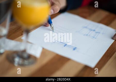 The hand of the designer with a pen, designing and sketching his idea for a furniture product Stock Photo