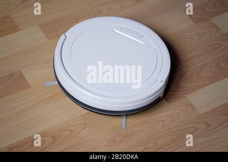 robotic or robot vacuum cleaner cleaning laminate floor Stock Photo