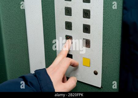 Pressing the button in the elevator. Male hand in a jacket. Elevator cabin in a residential building Stock Photo