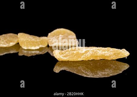Group of four slices of dried yellow pineapple isolated on black glass Stock Photo