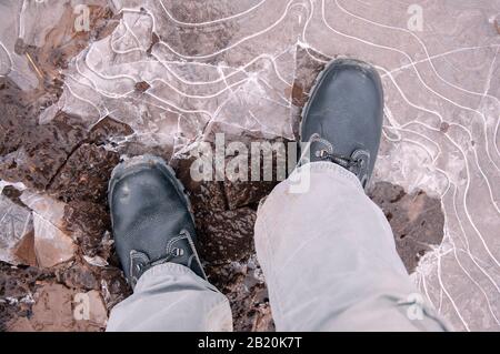 Black work boots on ice covered ground. Work shoes for work. Stock Photo