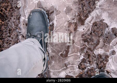 Black work boots on ice covered ground. Work shoes for work. Stock Photo
