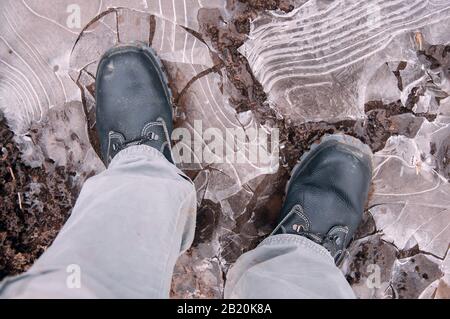 Black work boots on ice covered ground. Work shoes for work. Stock Photo