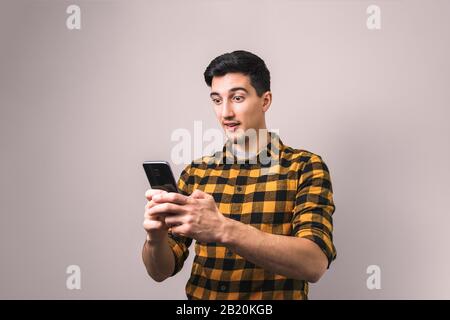 young man looking into his phone amazed by unbelievable news or social media post Stock Photo