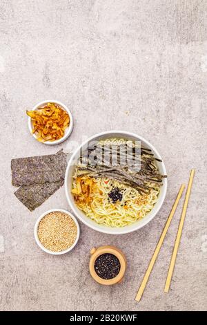 Noodles with seaweed, tuna flakes and sesame seeds. Healthy vegan (vegetarian) eating. In ceramic bowls, stone concrete background, copy space, top vi
