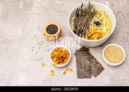 Noodles with seaweed, tuna flakes and sesame seeds. Healthy vegan (vegetarian) eating. In ceramic bowls, stone concrete background, copy space