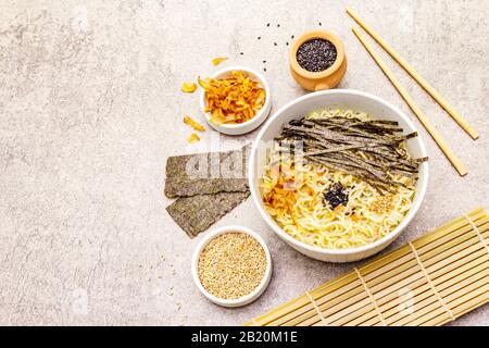 Noodles with seaweed, tuna flakes and sesame seeds. Healthy vegan (vegetarian) eating. In ceramic bowls, stone concrete background, copy space