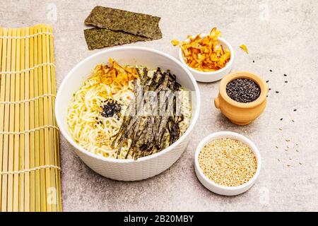 Noodles with seaweed, tuna flakes and sesame seeds. Healthy vegan (vegetarian) eating. In ceramic bowls, stone concrete background, close up