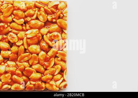 A large tile of roasted peanuts bar in a sweet molasses on a white background. Kozinaki useful and tasty sweets of the East. Top view, isolated. Stock Photo