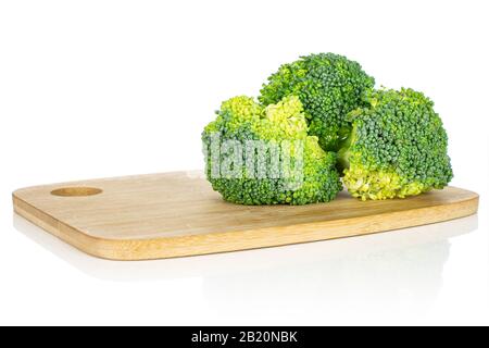 Group of three whole fresh green broccoli head on bamboo cutting board isolated on white background Stock Photo