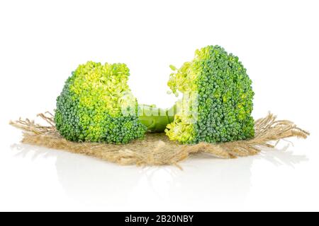 Group of two whole fresh green broccoli head on natural sackcloth isolated on white background Stock Photo