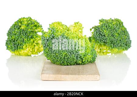 Group of three whole fresh green broccoli head on small wooden cutting board isolated on white background Stock Photo