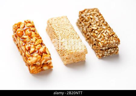 Grain granola bar with peanuts, sesame and seeds in a row on a white background. Top view Kozinaki Three assorted bars, isolate Stock Photo