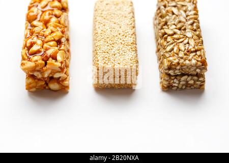 Grain granola bar with peanuts, sesame and seeds in a row on a white background. Top view Kozinaki Three assorted bars, isolate Stock Photo