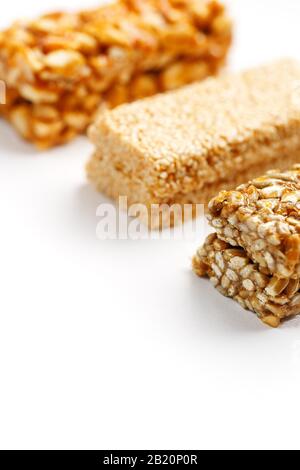 Grain granola bar with peanuts, sesame and seeds in a row on a white background. Top view Kozinaki Three assorted bars, isolate Stock Photo