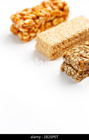 Grain granola bar with peanuts, sesame and seeds in a row on a white background. Top view Kozinaki Three assorted bars, isolate Stock Photo