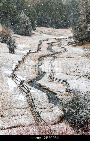 Post and rail fence and stream in fresh winter snow; near Salida; Colorado; USA Stock Photo