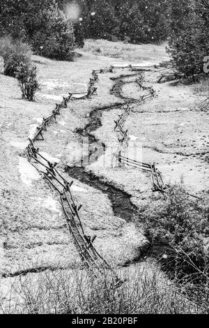 Black & shite view of post and rail fence and stream in fresh winter snow; near Salida; Colorado; USA Stock Photo