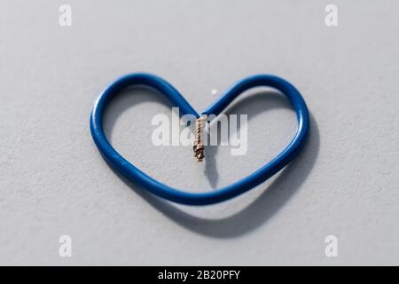 A small heart  made from blue cables on a gray background Stock Photo