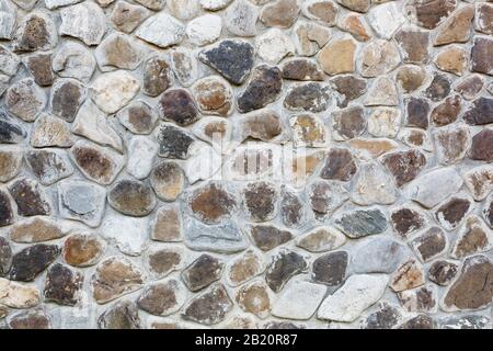 Large wall of natural stones of different size and colored gray texture on a summer day Background Stock Photo