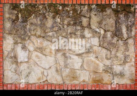 Wall of natural light stone in a red brick frame. Background, texture Stock Photo