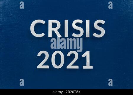 the words crisis 2021 laid with silver metal letters on blue surface for stock market strategy background Stock Photo