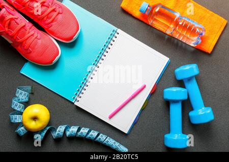 Notepad, a bottle of water, an apple, a skipping rope, dumbbells. Healthy diet, lifestyle concept of dumbbells, exercise, sport Stock Photo