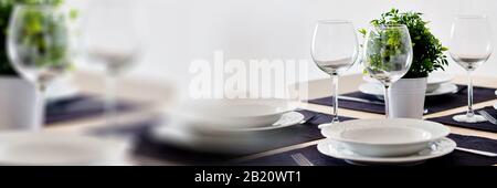 Close up view table setting served for dinner on violet place mats empty wine glasses plates flatware, no people. Horizontal image with copy space Stock Photo