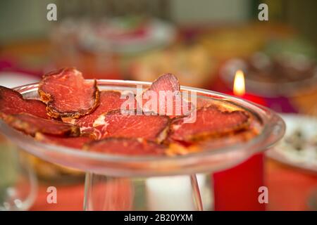 close-up of red slices of iberian loin on glass dish and multicolored background Stock Photo