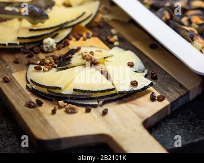 view of cured cheese cut into triangles on a wooden board and nuts Stock Photo