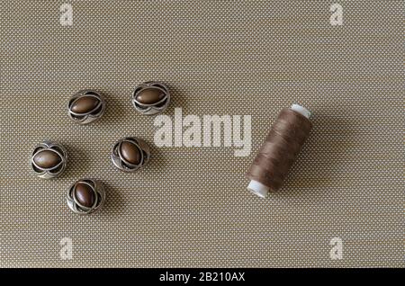 Buttons and threads background. Five buttons and spools of thread on a textured table. View from above. Selective focus. Conceptual background. Select Stock Photo