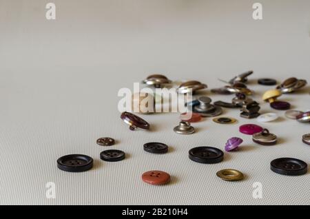 Multi-colored buttons background. Used buttons on a light textured surface. Side view. Selective focus. Eye level shooting. Stock Photo
