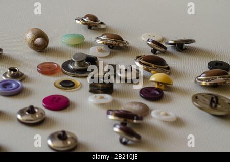 Various sewing accessories close-up. Used multi-colored buttons on a light textured surface. Side view. Focus in the background. Eye level shooting. Stock Photo