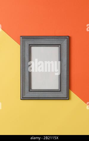 Blank gray wooden photo frame on geometric yellow and orange background Stock Photo