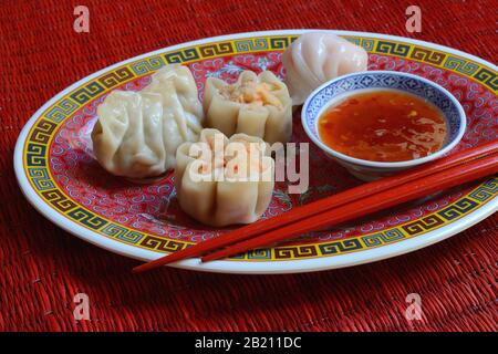 Dim Sum, filled dumplings on plate with red chopsticks and chilli sauce, Germany Stock Photo