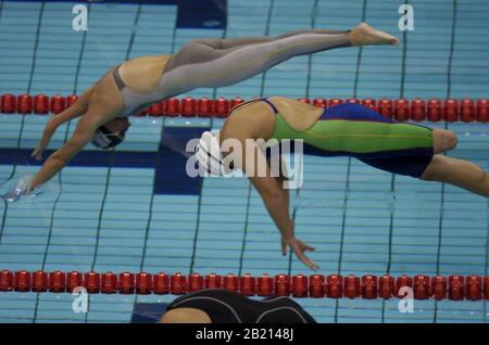 Athens, Greece 19SEP04:  South Africa's Natalie du Toit (green and blue suit) takes off in the women's 100-meter freestyle S9 event at the Athens Paralympics.  Du Toit won the event for her second medal.  ©Bob Daemmrich Stock Photo