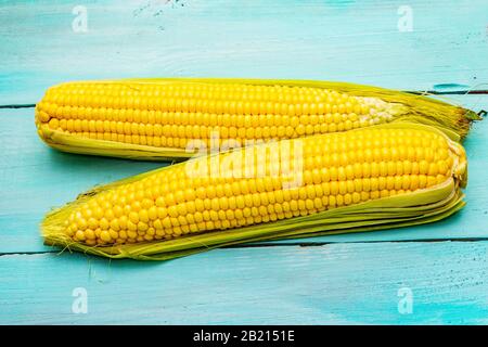 Fresh sweet corn on cobs. Natural organic raw vegetables, healthy food concept. On rustic turquoise wooden boards background, copy space Stock Photo