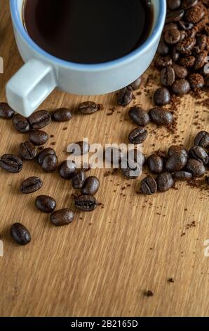 Cup of black coffee on a table, surrounded by scattered coffee beans Stock Photo