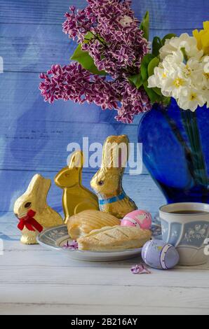 Delicious easter still life for mom has pastries chocolate bunnies, a vase with flowers and a decorated egg Stock Photo