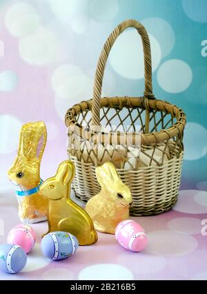 An empty basket is ready to be filled with colorful easter eggs and gold wrapped chocolate easter bunnies Stock Photo