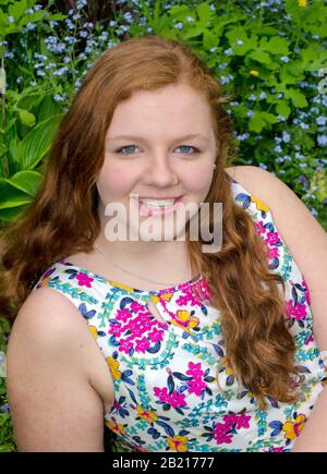 Pretty teen girl in a flowered dress posed in a field of flowers Stock Photo