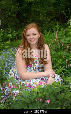 A beautiful teen girl poses for high school graduation photos in a colorful garden Stock Photo