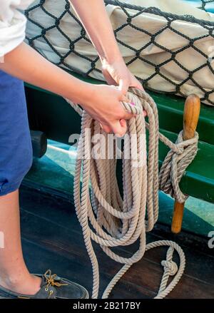 A sailor secures thick rope with a neat sailors knot, along the side of this tall ship on Lake Michigan USA Stock Photo