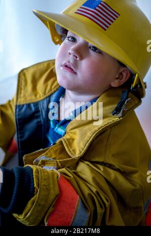 A young boy dresses up in a firefighter costume complete with hard hat Stock Photo