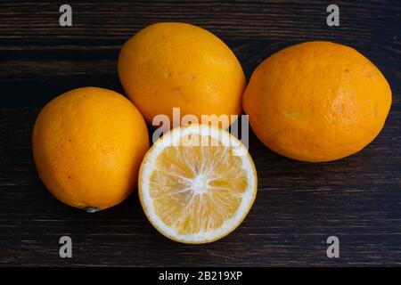 Meyer Lemons on a Wood Background: A group of organic citrus fruits on a dark wooden cutting board Stock Photo