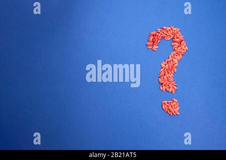 question mark right from cucumber seeds, processed, colored red on blue background, with place for text Stock Photo