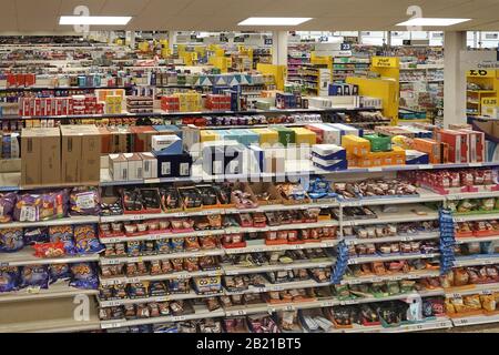 Interior view top shelf overstock merchandise in cardboard box packaging above shopping aisle shelves in large food supermarket London England UK Stock Photo