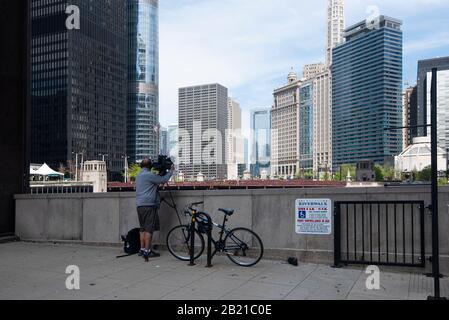 A lone cameraman filming from Dearborn Street Bridge towards the University of Chicago and State Street Bridge Stock Photo