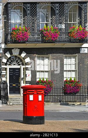 Double Royal Mail red GR pillar post box & closed plates on slots located at Bedford Square Georgian property & window box balcony flowers London UK Stock Photo